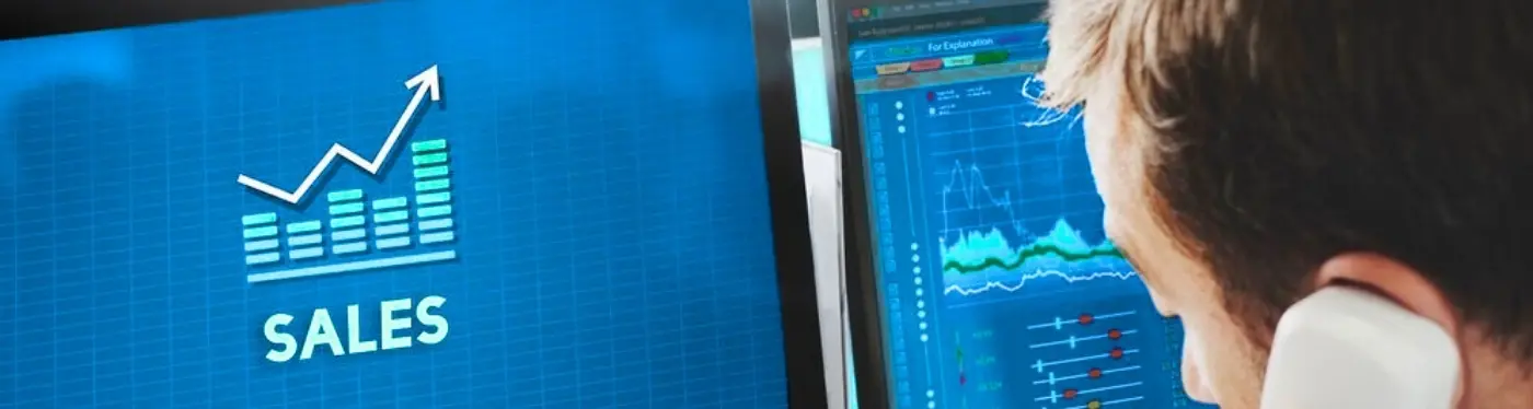 Sales graph on a computer screen with a businessman analyzing data while on a call.